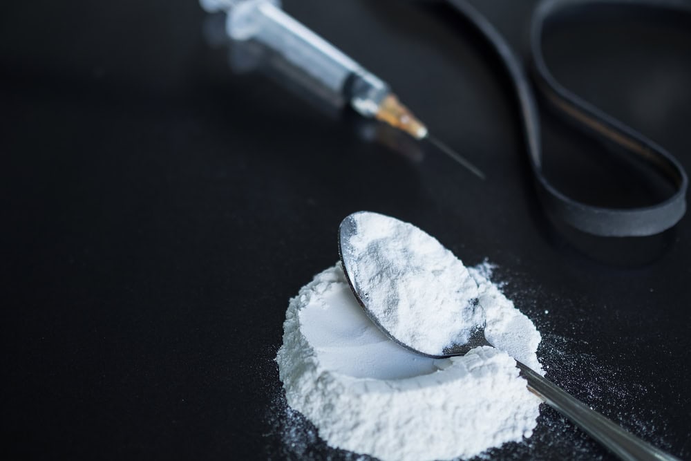 powder morphine on spoon and morphine in syringe with black rubber band on black wood background. Illegal drug. addictive substance, narcotic, habit-forming substance concept.