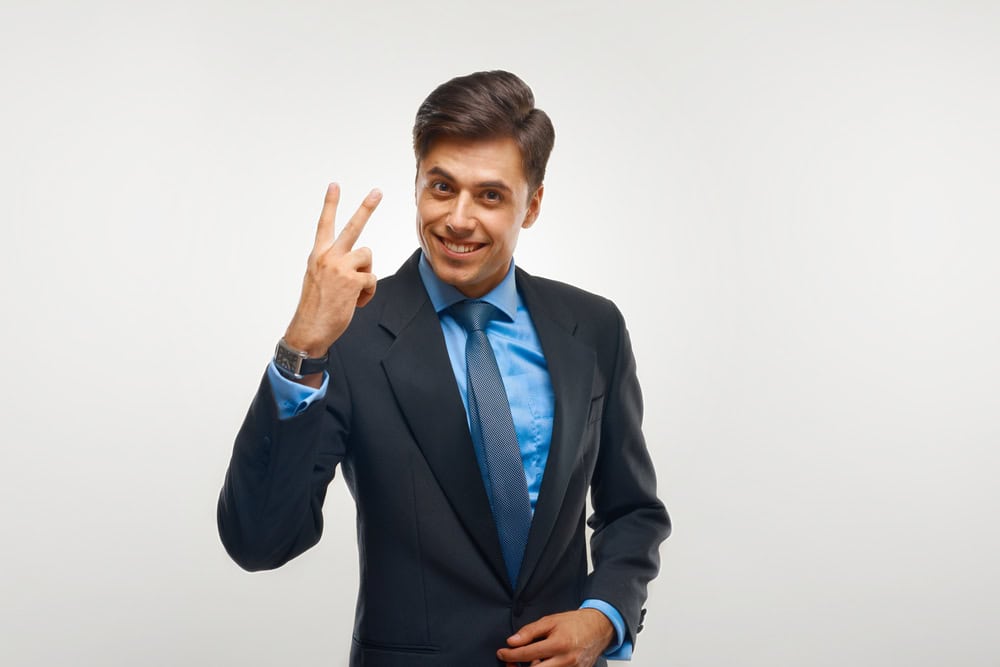 Closeup of a young business man showing showing two number. 