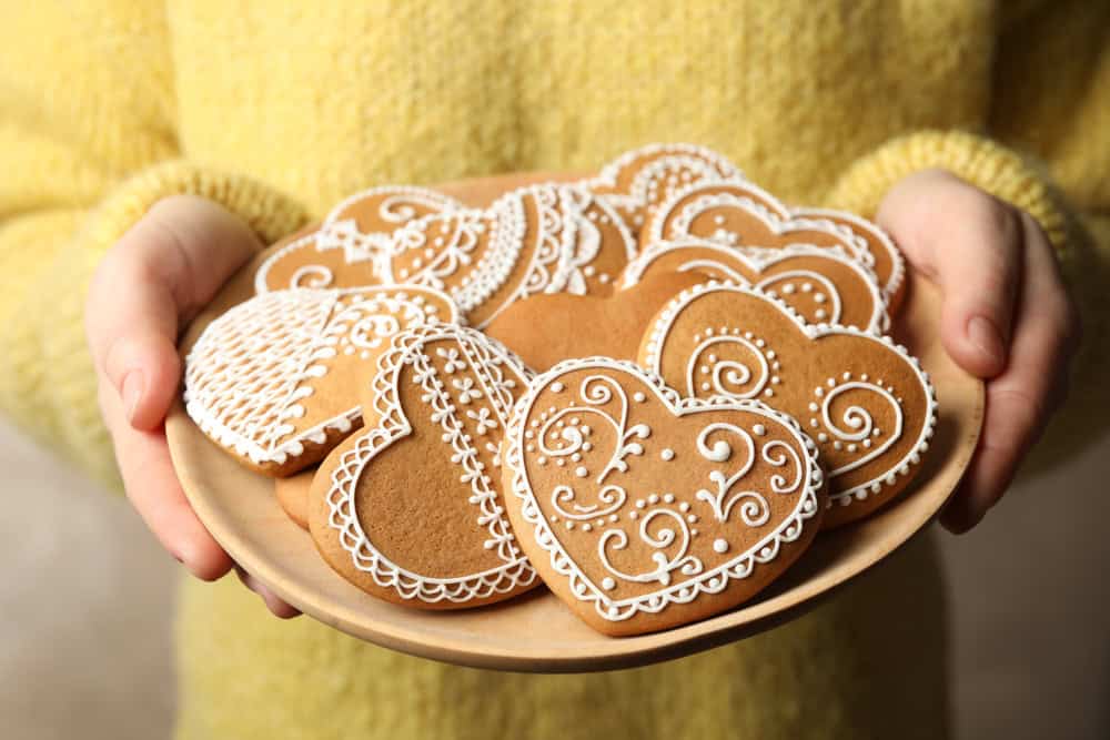 Woman holding plate with tasty heart shaped gingerbread cookies, closeup