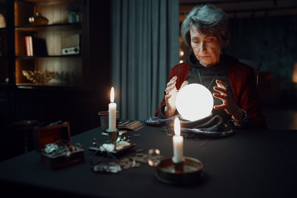Confident fortune teller doing predictions with illuminated crystal ball