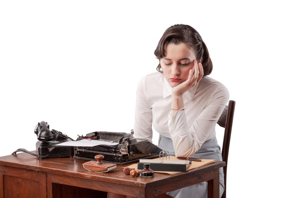 Sad bored vintage style secretary sitting at desk and working