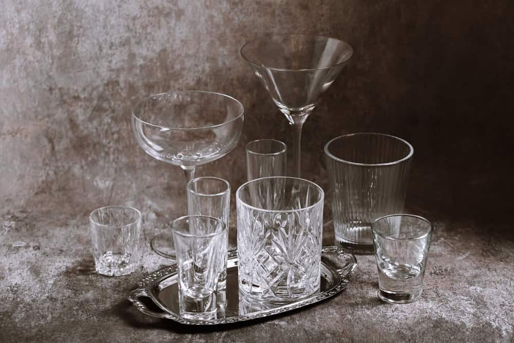 Collection of empty crystal glasses of varying sizes and shapes arranged elegantly on a textured tabletop