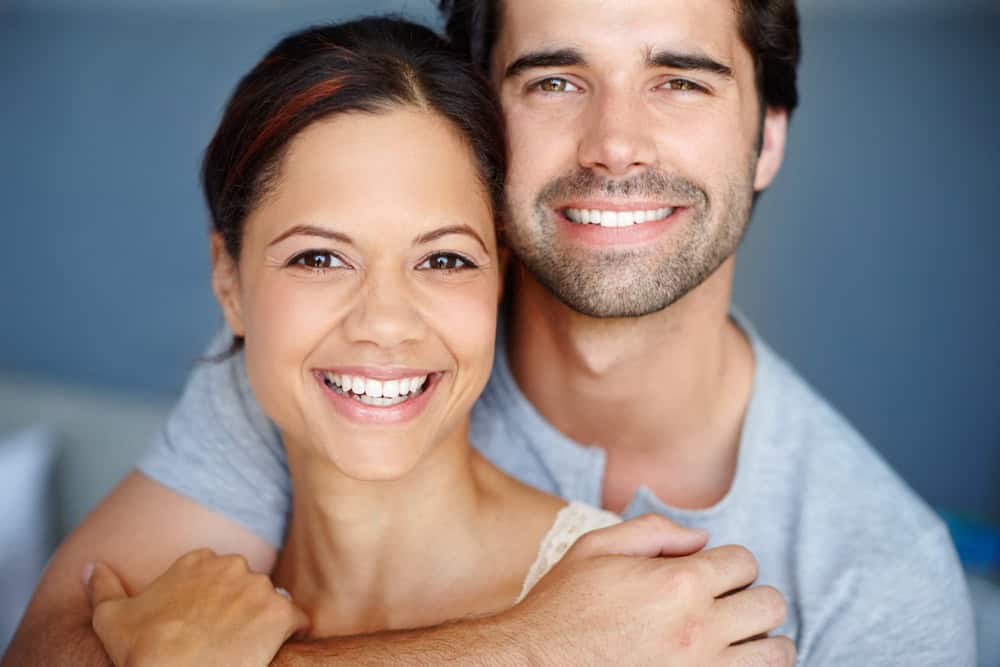 Hug, portrait and romance with couple in bedroom of home together for bonding, marriage or support. Face, love or trust with smile of man and woman embracing in apartment for weekend time off