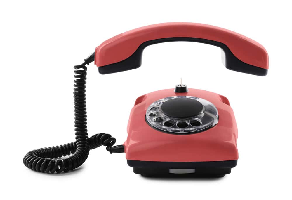 Old red telephone with rotary dial isolated on white