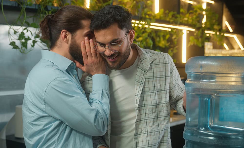 Arabian man drink water cooler in office coffee break pause two business men multiethnic businessmen colleagues coworkers Caucasian Indian guys friends talk secret gossip amazing news shock laughing