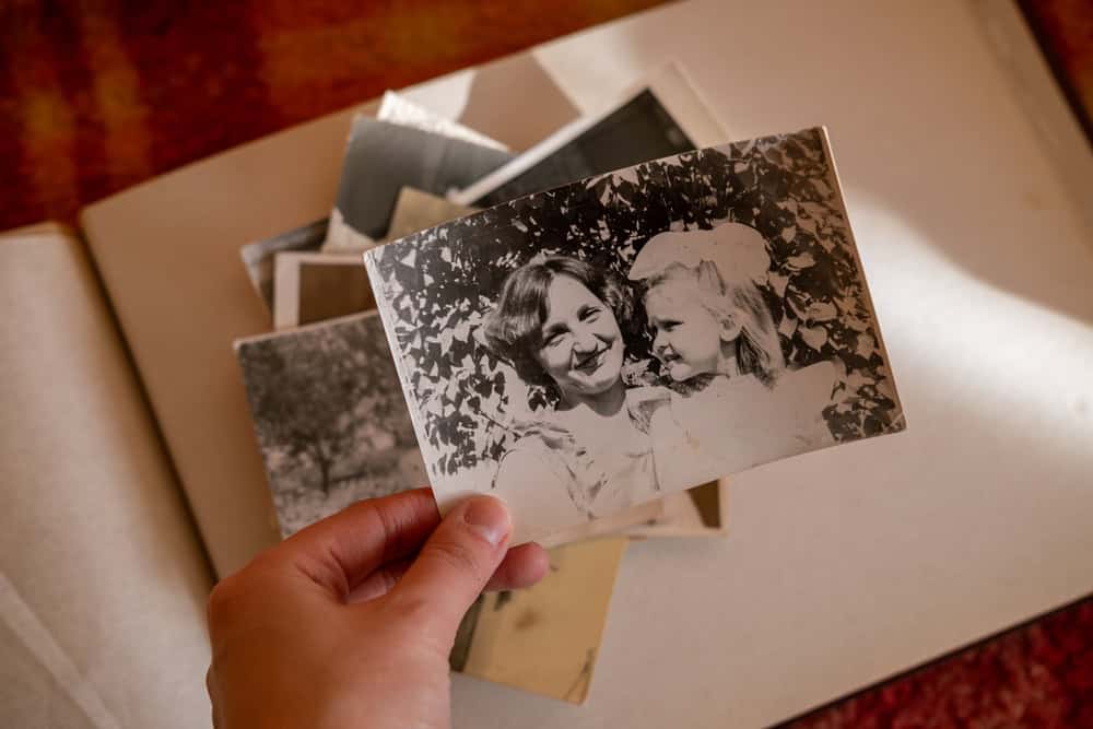 Uralsk, Kazakhstan - 22 January, 2025: Female hand is holding black and white old photo of her grandmother with her daughter. Vintage photo album with photos. Family and life values concept