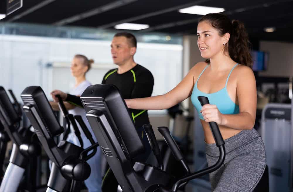 Fit young woman working out at elliptical machine in gym