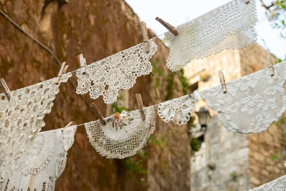 Handmade white lace doilies hanging on a clothesline in the historic coastal town of Perast, Montenegro, showcasing traditional local handicrafts. 