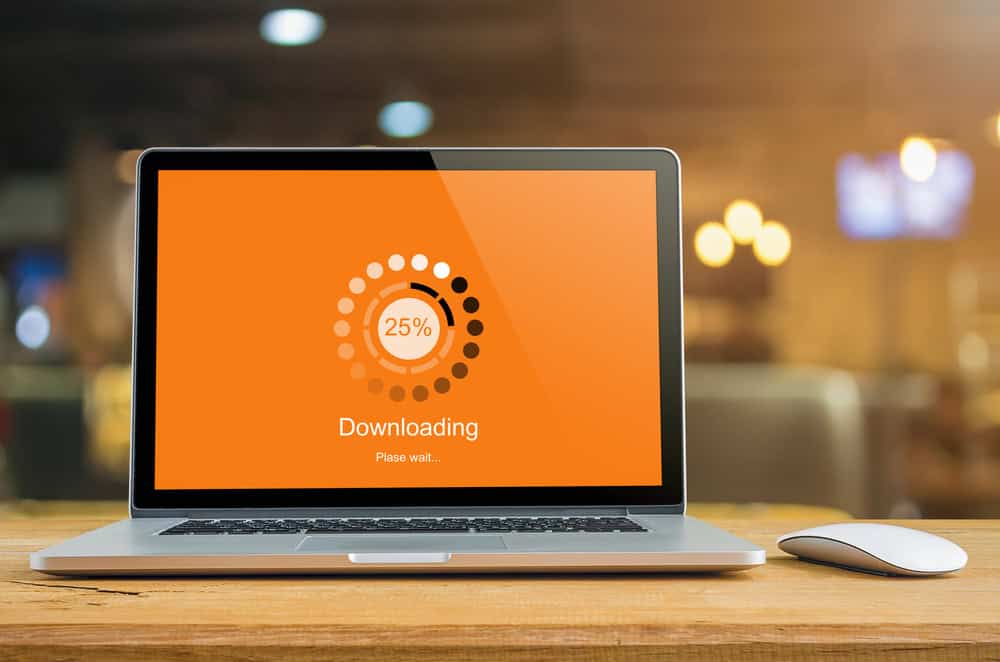 Laptop on table with Downloading bar load waiting on digital display, indicator concept.