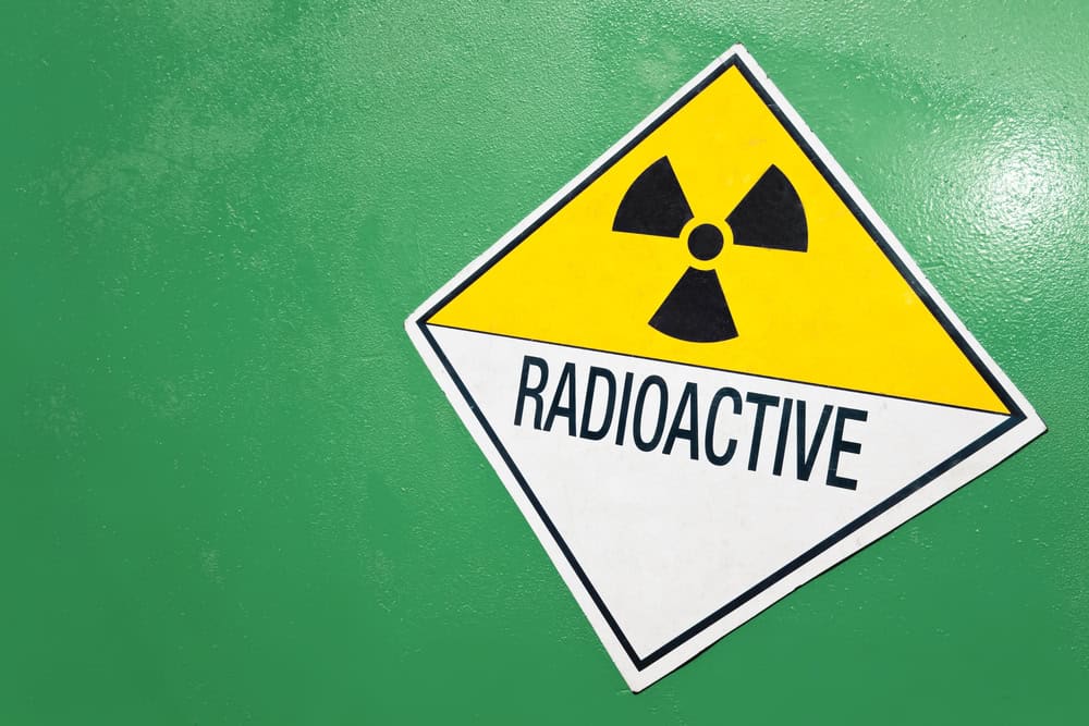 A radioactive warning sign on a green container of radioactive material