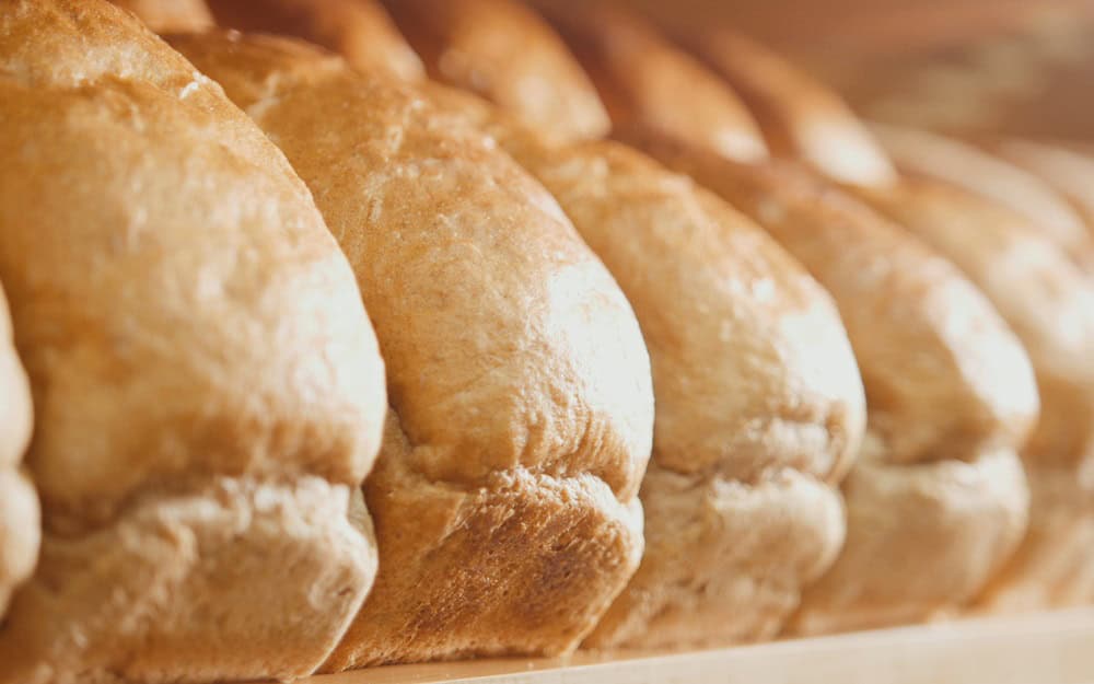 Many loaves of bread on a tray for sale